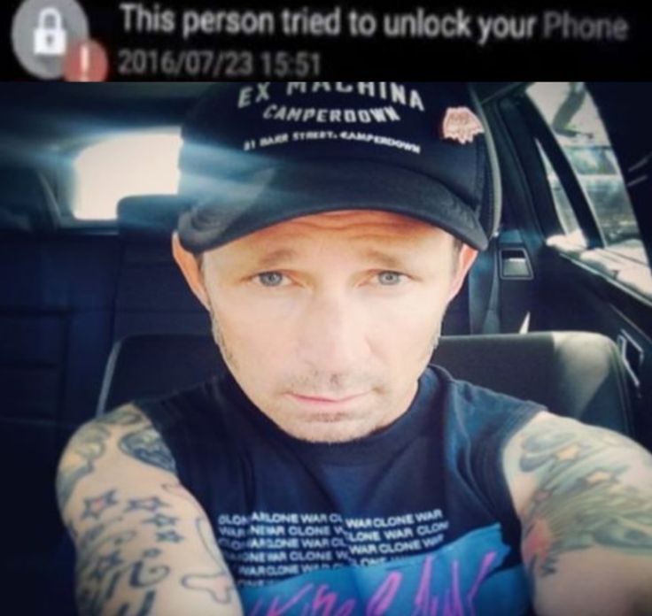 a man with tattoos on his arm in a car looking at the camera and taking a selfie