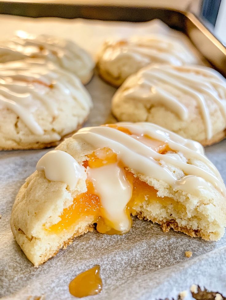 some biscuits with icing and oranges on top of them sitting on a baking sheet