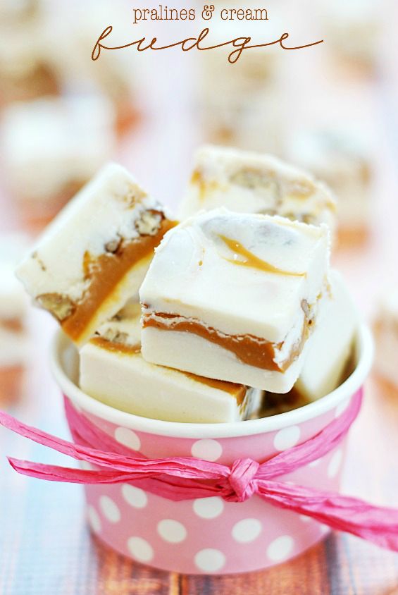 several pieces of white chocolate in a pink polka dot cup on a table with ribbon