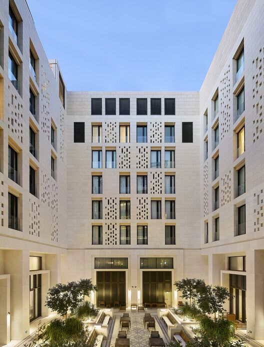 an outdoor courtyard with benches and tables in front of the building's windows at dusk