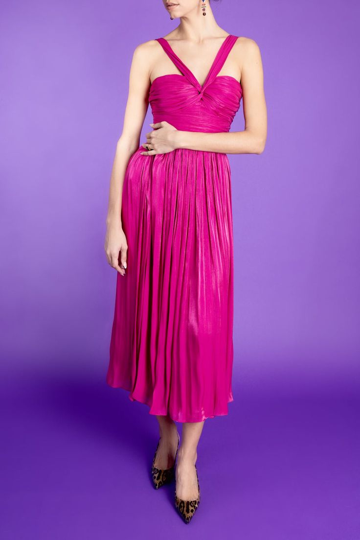 a woman in a pink dress standing against a purple background with her hands on her hips