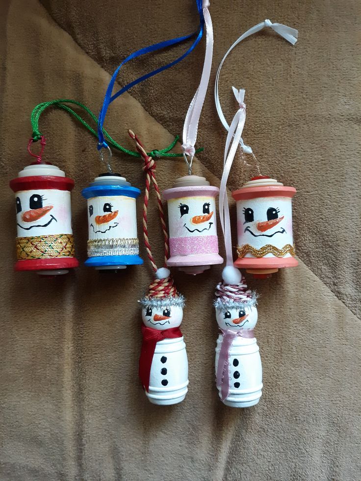 five christmas ornaments are hanging on a bed with a cord in the middle and one has a snowman ornament attached to it