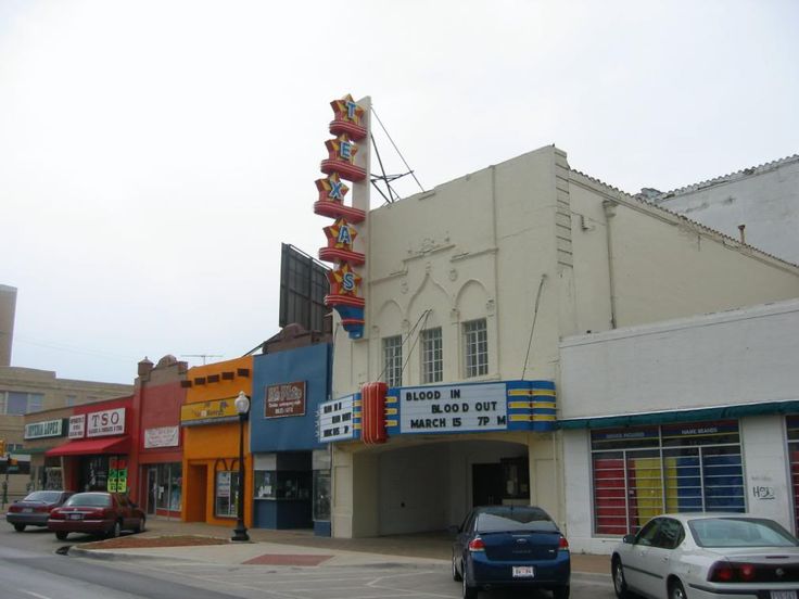 an old movie theater with cars parked in front