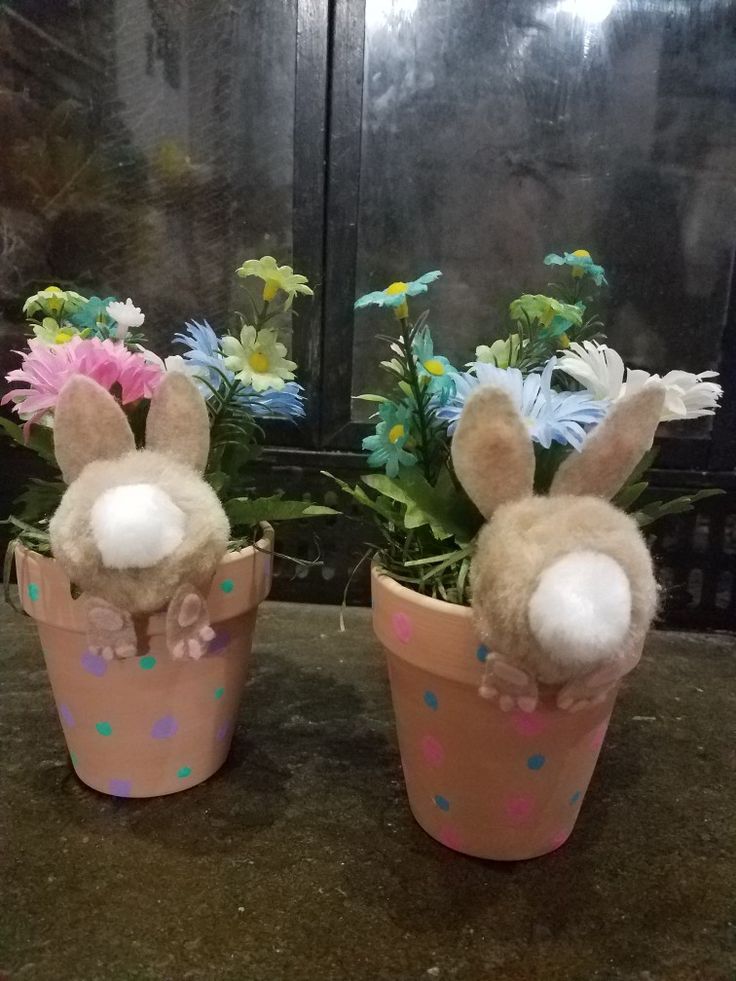 two stuffed animals sitting in flower pots on a table