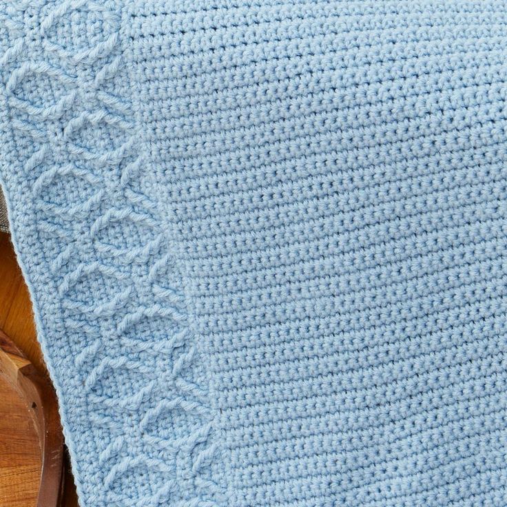 a blue crocheted blanket sitting on top of a wooden table