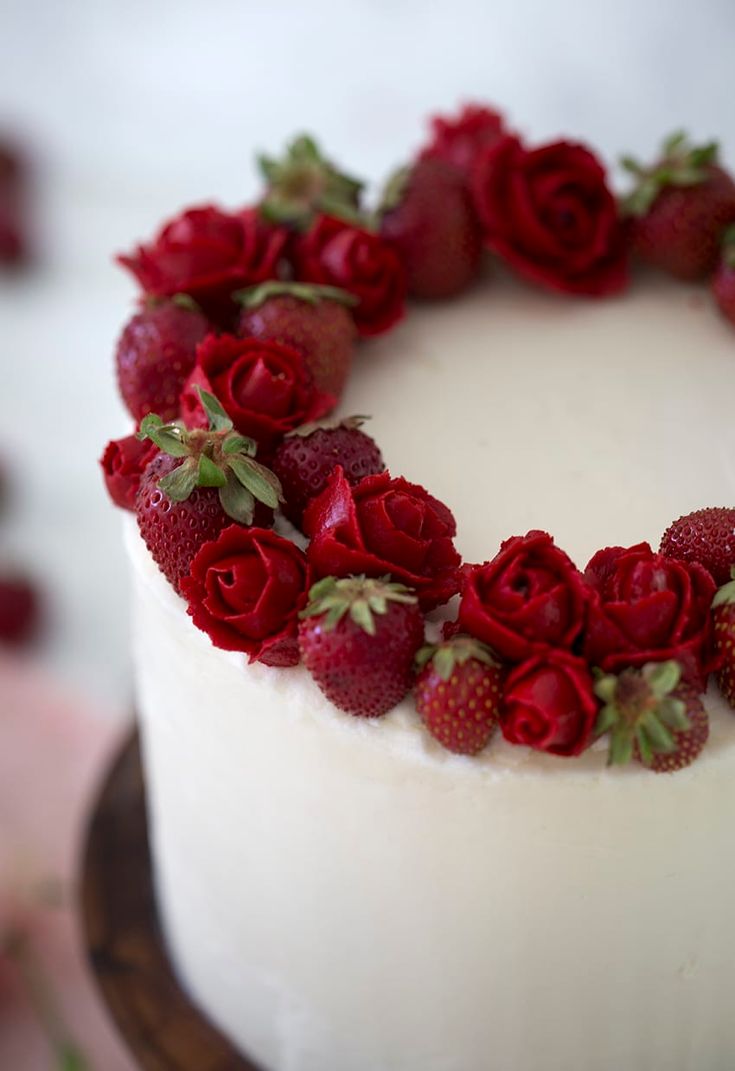 a white cake with strawberries and roses on top