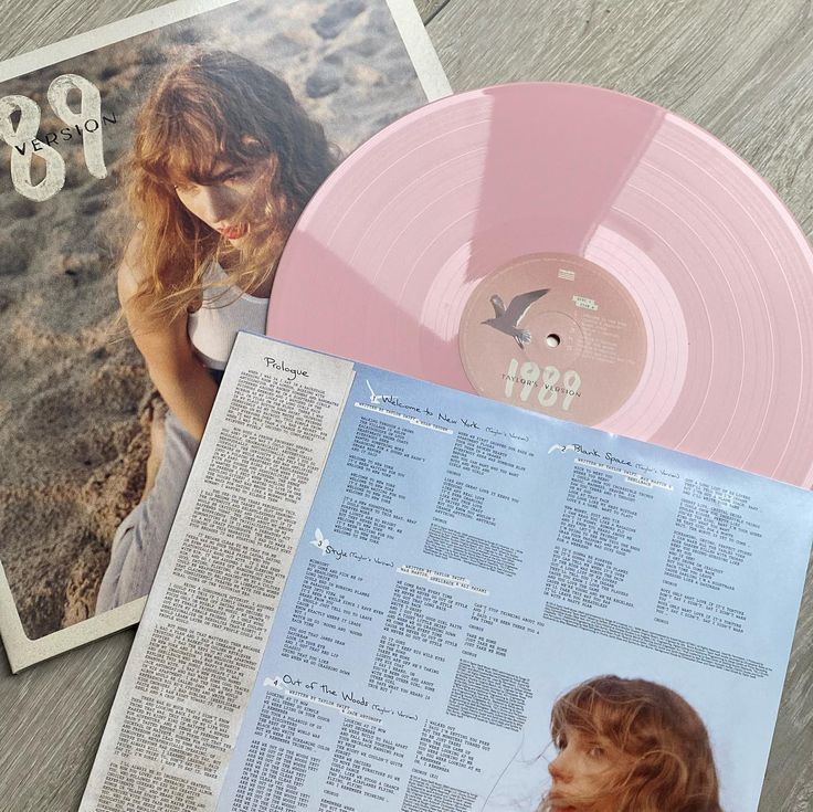 a pink vinyl record sitting on top of a wooden table next to an old magazine