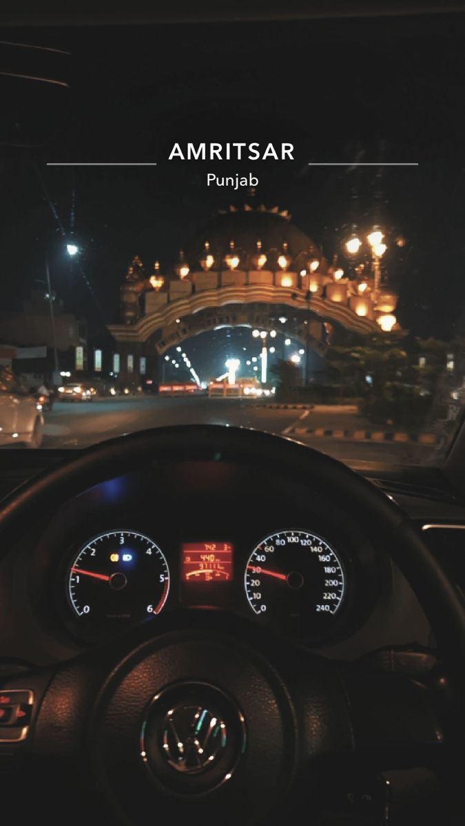 the dashboard of a car at night in front of a building with lights on it