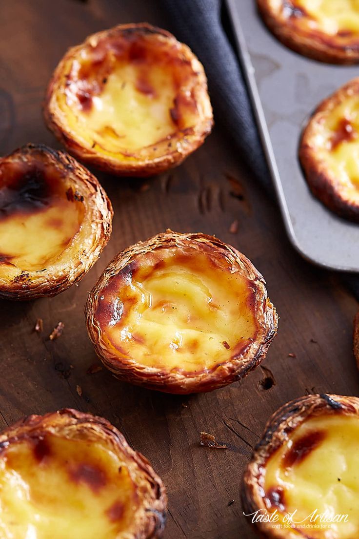 mini cheese pies on a wooden table next to a cookie sheet