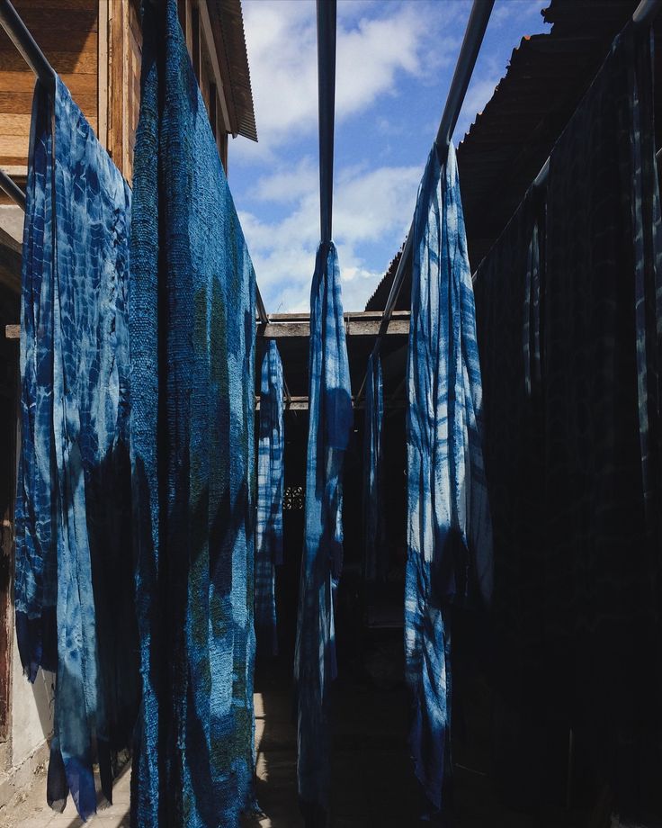 several blue cloths are hanging outside in the sun