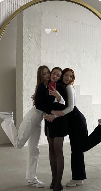 three young women are hugging in front of a mirror with their arms around each other