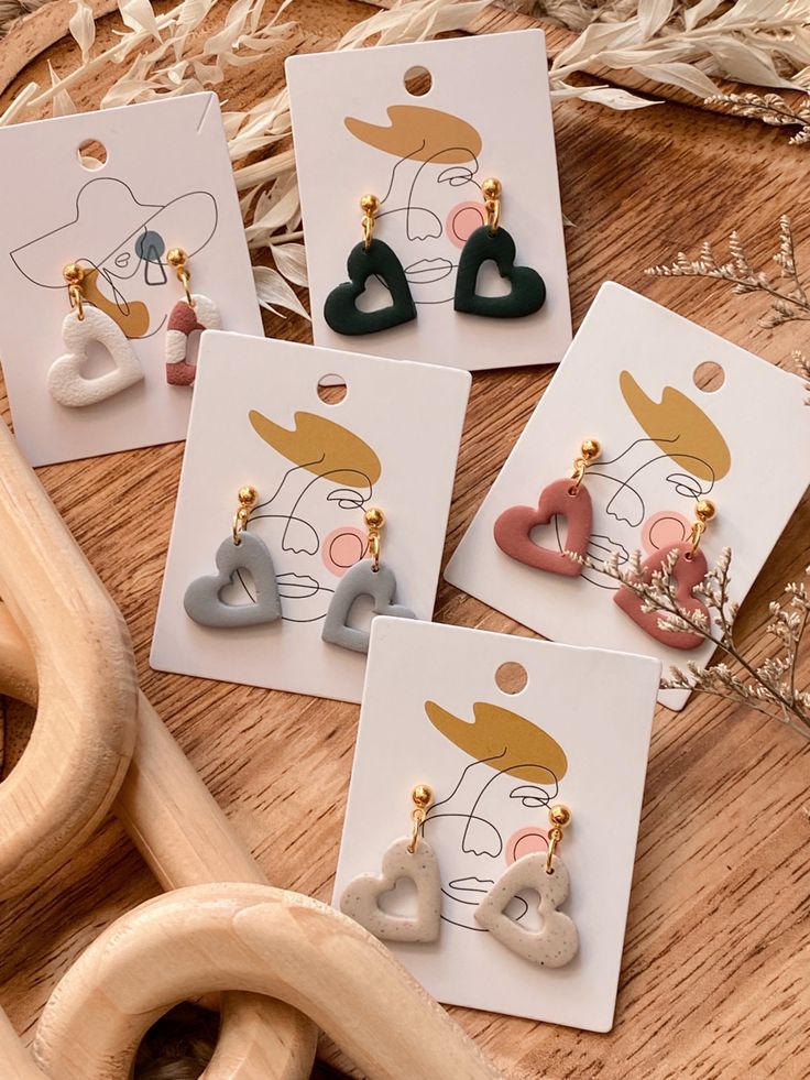 four pairs of heart shaped earrings sitting on top of a wooden table