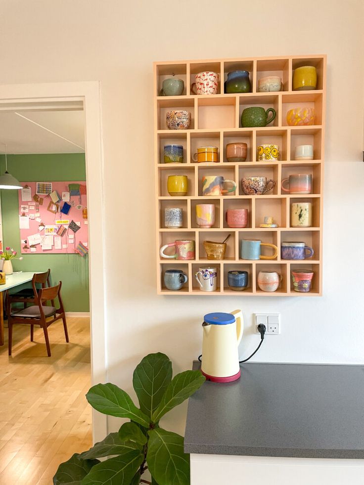 there is a coffee pot on the counter next to a vase with flowers in it