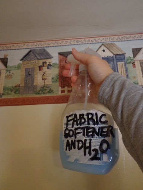 a person holding a plastic bottle in front of a wall with some pictures on it