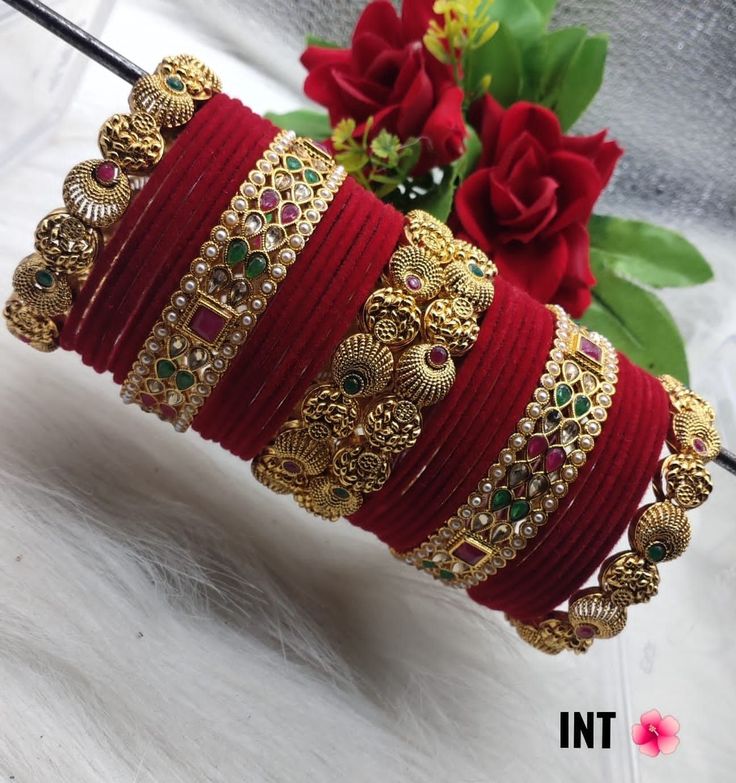 a bunch of red bracelets sitting on top of a white furnishing next to a bouquet of flowers