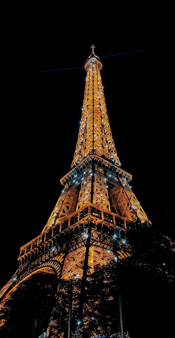 the eiffel tower lit up at night with lights on it's sides