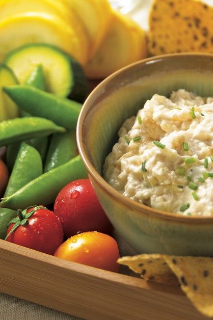 a bowl of dip surrounded by vegetables and fruit