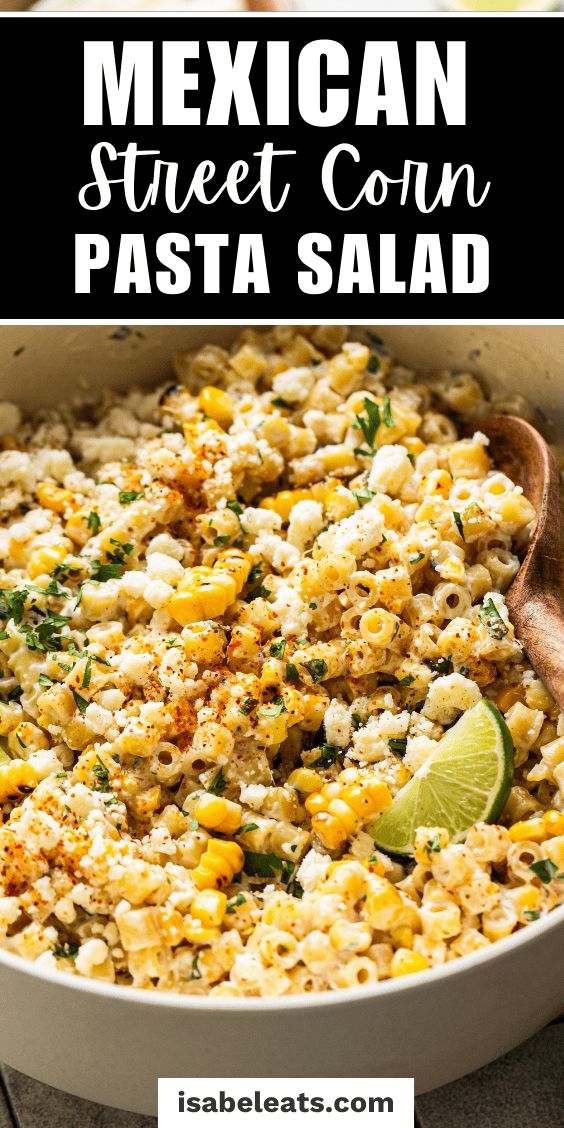 mexican street corn pasta in a white bowl with a wooden spoon and lime wedges on the side