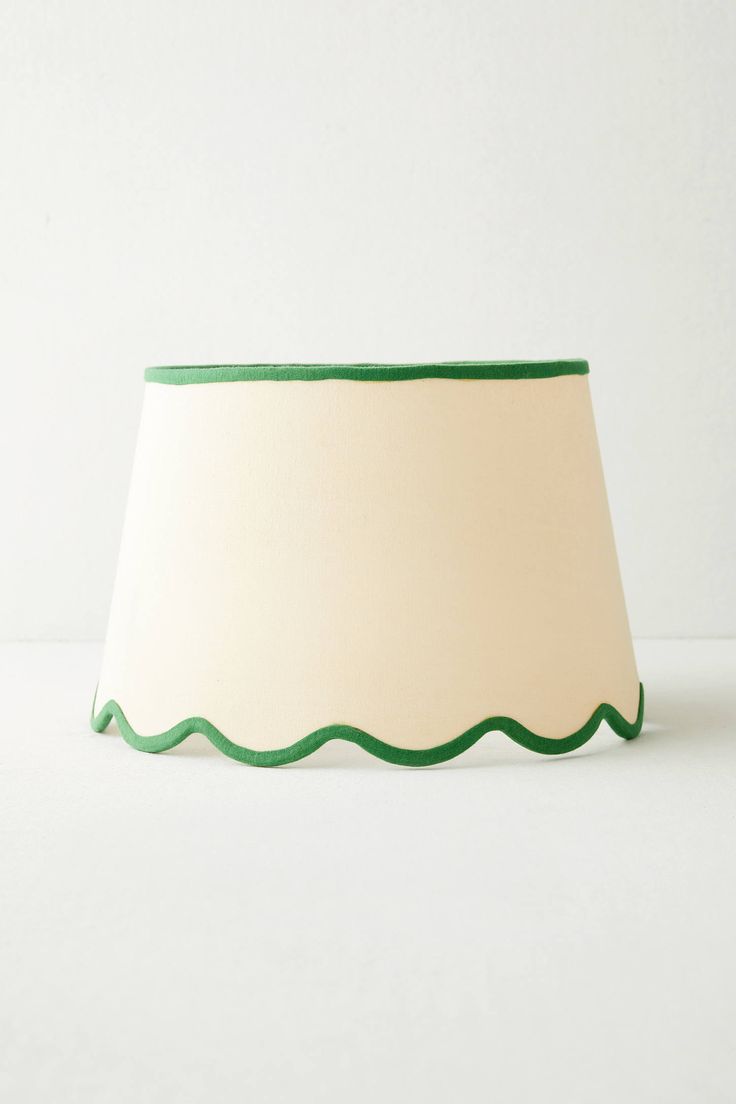 a green and white lamp shade with scalloped edges on a white wall background