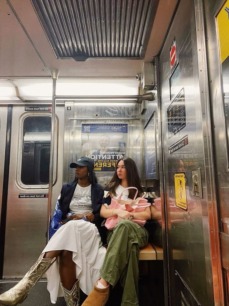 two people sitting on a subway train next to each other