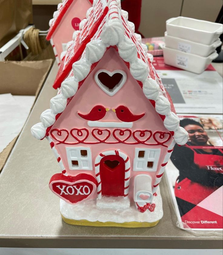 a gingerbread house is decorated with red and white icing for valentine's day