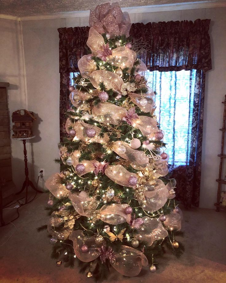 a decorated christmas tree in a living room with pink and white ornaments on the top