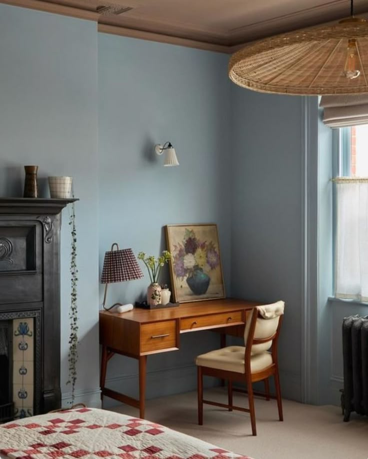 a bedroom with blue walls and a wooden desk