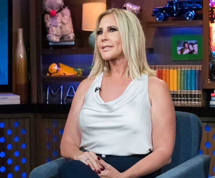 a woman sitting in a blue chair with her hands on her hips and looking off to the side