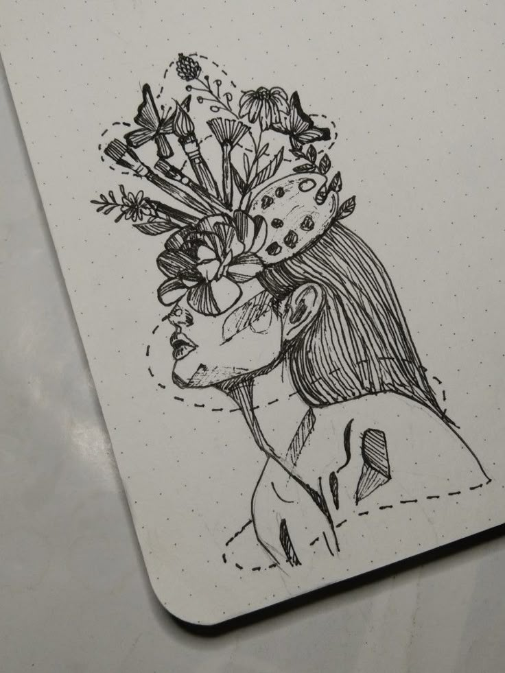 a drawing of a girl with flowers in her hair on top of a notepad