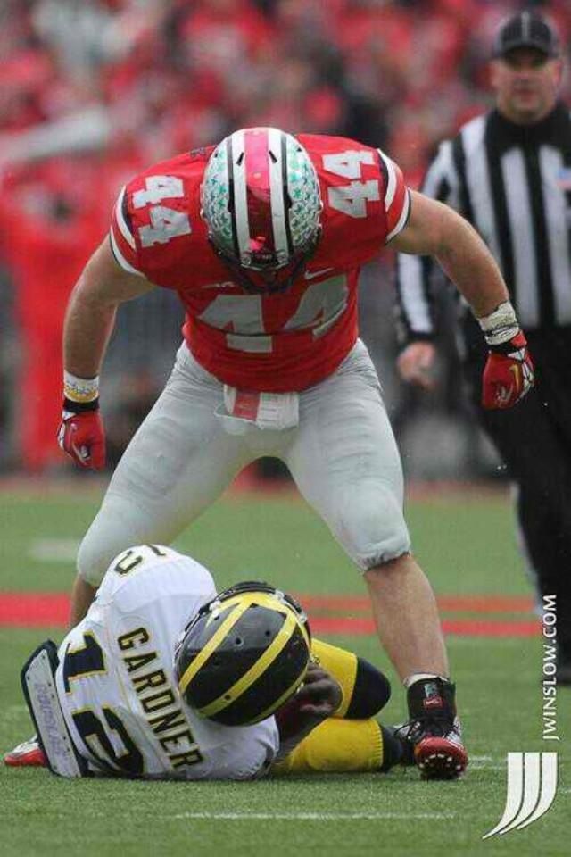 a football player kneeling down on the ground with his head in his hands and another person standing next to him