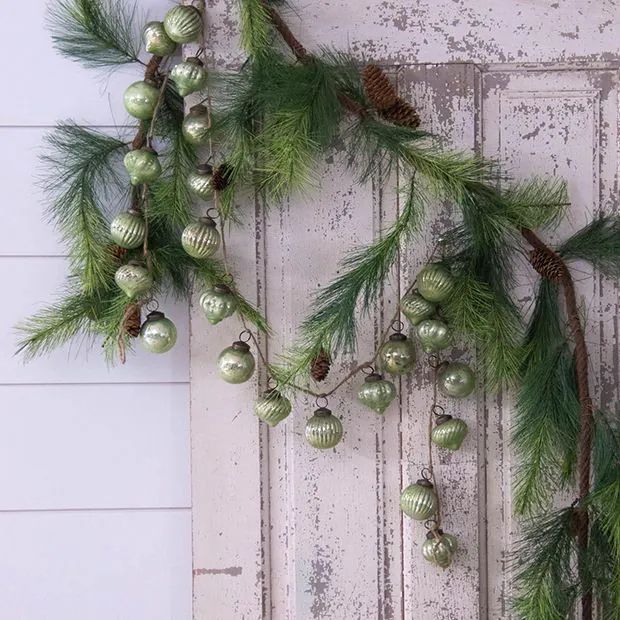 christmas decorations hanging on the side of a door with pine cones and ornaments around it