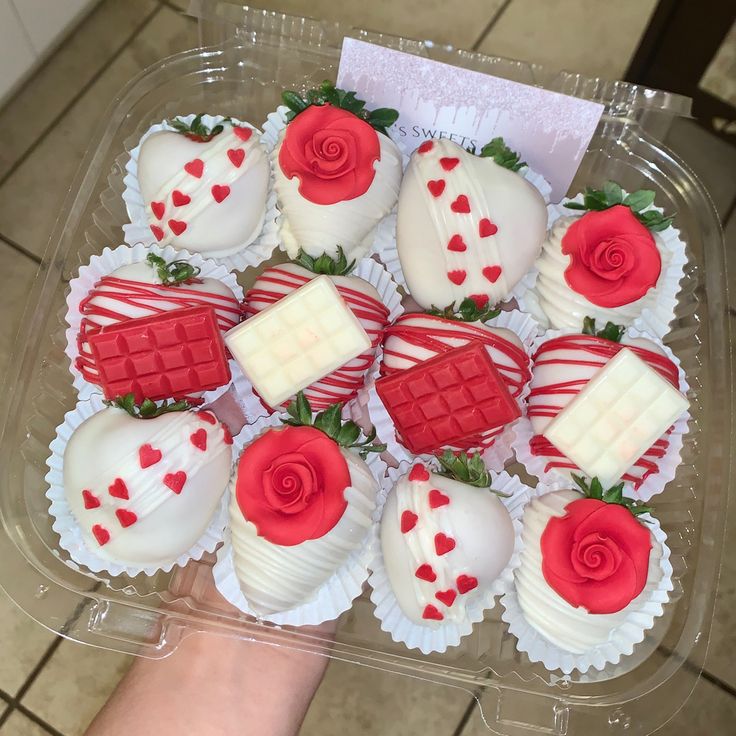 a plastic container filled with lots of heart shaped chocolates covered in white and red frosting