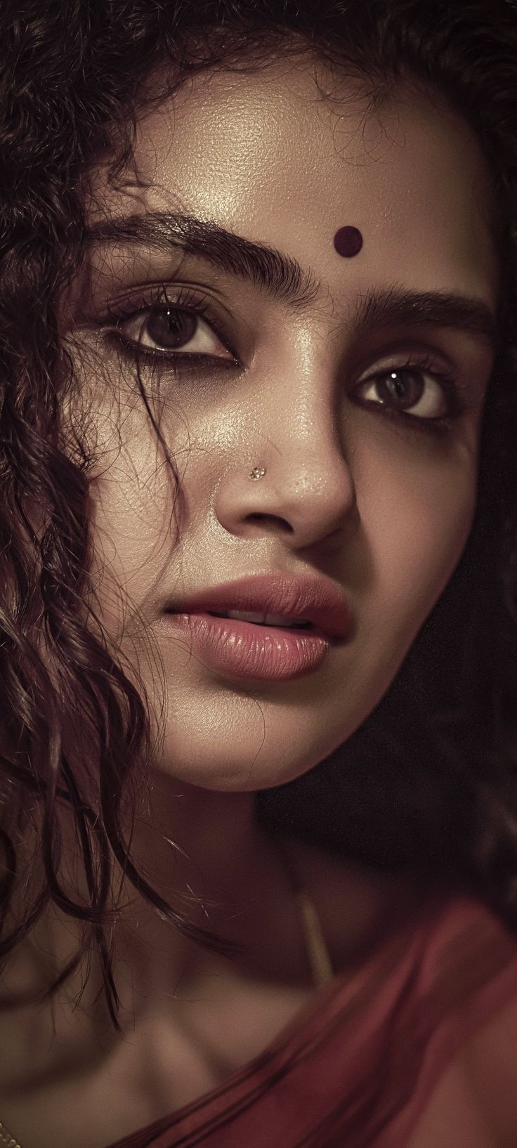 a woman with curly hair and piercings on her forehead is posing for a photo