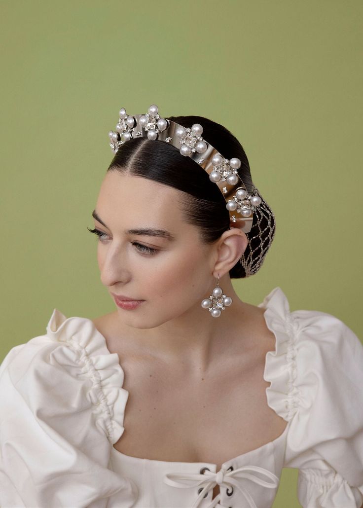 The Tudor Crown and its accompanying suite are the embodiment of classics re-imagined. Breathing life into the regality of design these stunning headbands have no comparison. Swarovski and pearl come together in perfect harmony in a way they were meant to. The Tudor Crown is as beautiful as it is comfortable and wearable and has the capability to elevate like no other headband can. Made in NYC.*The Tudor Crown in Silver is MADE TO ORDER and takes 2-3 weeks for shipment* Elegant Gold Teardrop Crown Headband, Elegant Formal Jewelry With Tall Crown, Elegant Crystal Embellished Jewelry Headband, Elegant Silver Hair Accessories For Evening, Elegant Crown Hair Accessories For Parties, Luxury Wedding Headpieces, Luxury Formal Headpiece With Structured Crown, Elegant Evening Headpiece With Structured Crown, Elegant Tall Crown Headband For Parties