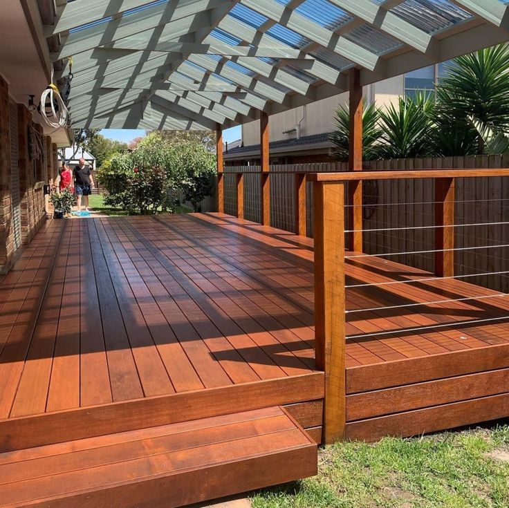 a wooden deck with metal railings under a glass roof