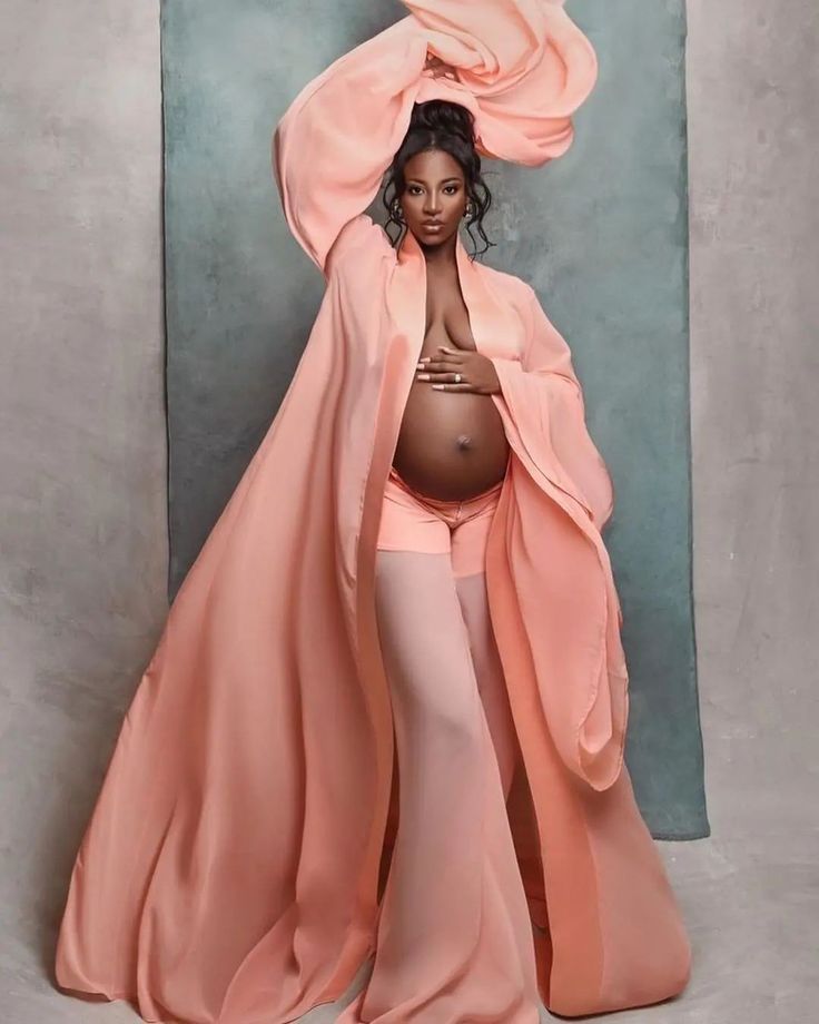 a pregnant woman in a pink gown and matching shawl poses for a photo shoot