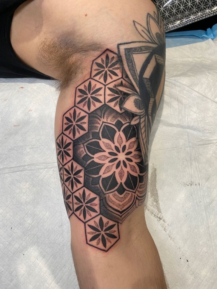 a man's leg with a tattoo on it that has an abstract flower design