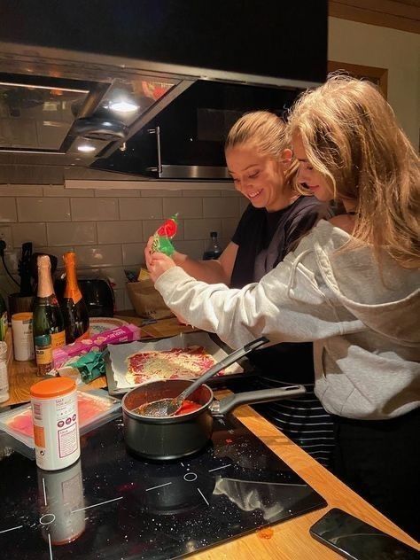 two women in a kitchen preparing food on top of a stove with utensils