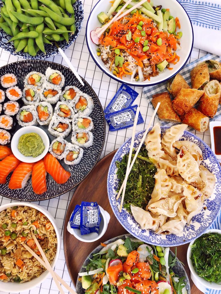 a table topped with plates of food next to bowls of vegetables and dipping sauces