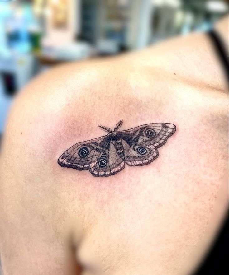 a small butterfly tattoo on the back of a woman's left upper arm and shoulder