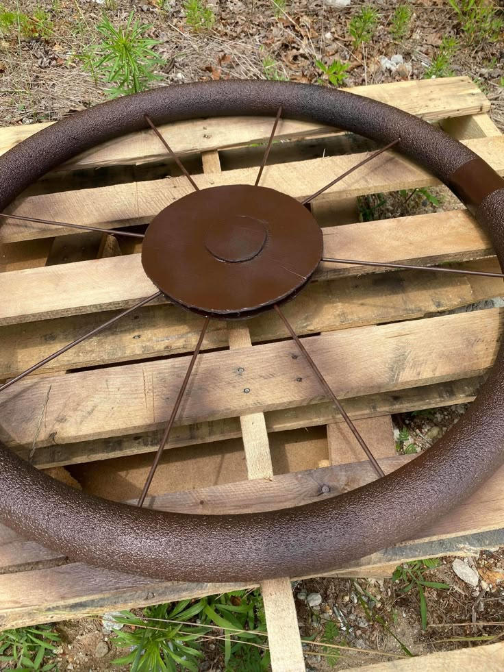 an old steering wheel is sitting on some wood