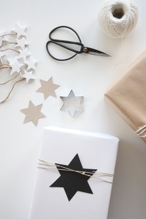 wrapping paper, scissors and twine on top of a white table with star decorations