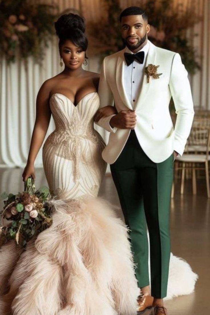 two people standing next to each other wearing tuxedos and gowns with feathers on them