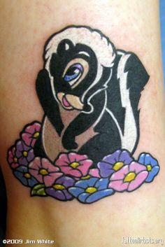 an animal tattoo on the leg of a woman's leg, with flowers around it