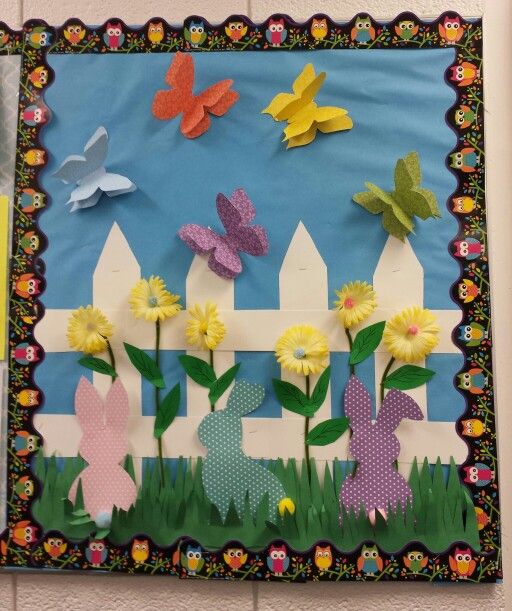 a bulletin board with paper flowers and bunnies on the front, butterflies in the background