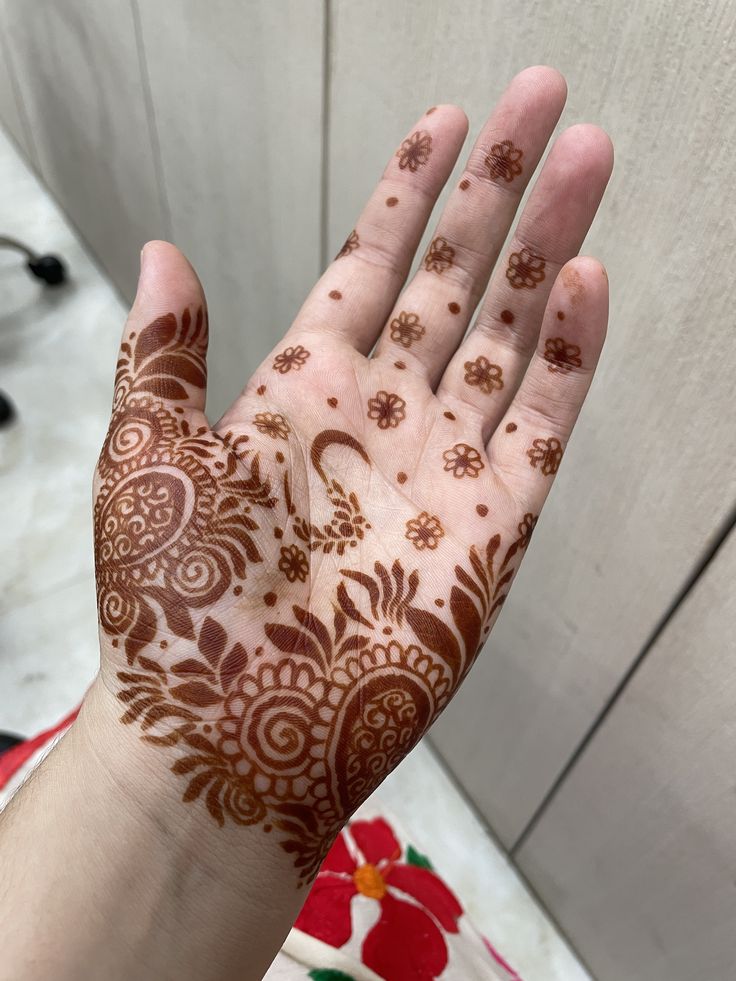 a person's hand with henna on it and flowers painted on the palm