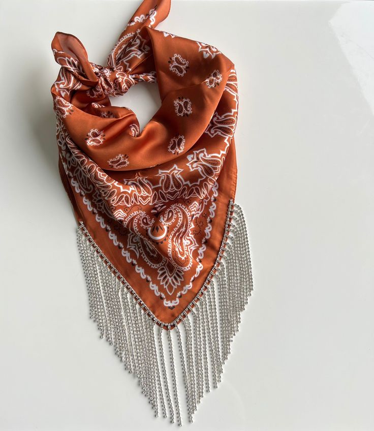 an orange and white scarf with tassels hanging from it's end on a table