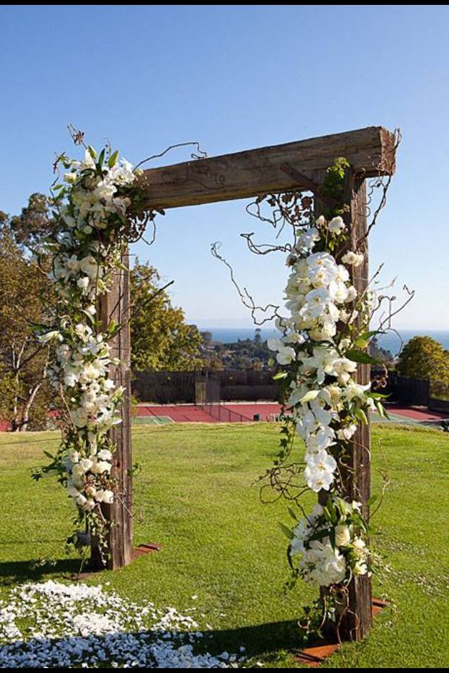 wedding flowers and greenery are arranged around the ceremony arch