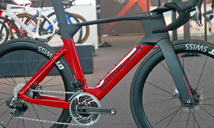 a close up of a red bike on display at a bicycle show with other bikes in the background