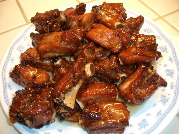 a white and blue plate topped with meat on top of a kitchen counter next to a tiled floor